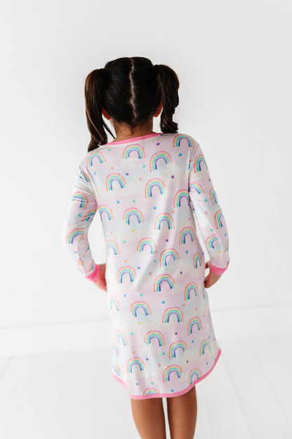 Child wearing a nightgown with rainbow pattern on a white background