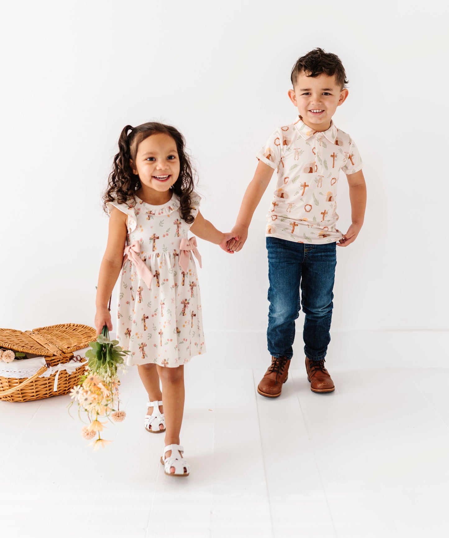 Two children, a girl and a boy, standing on a white background holding hands while wearing Easter-focused bamboo daywear