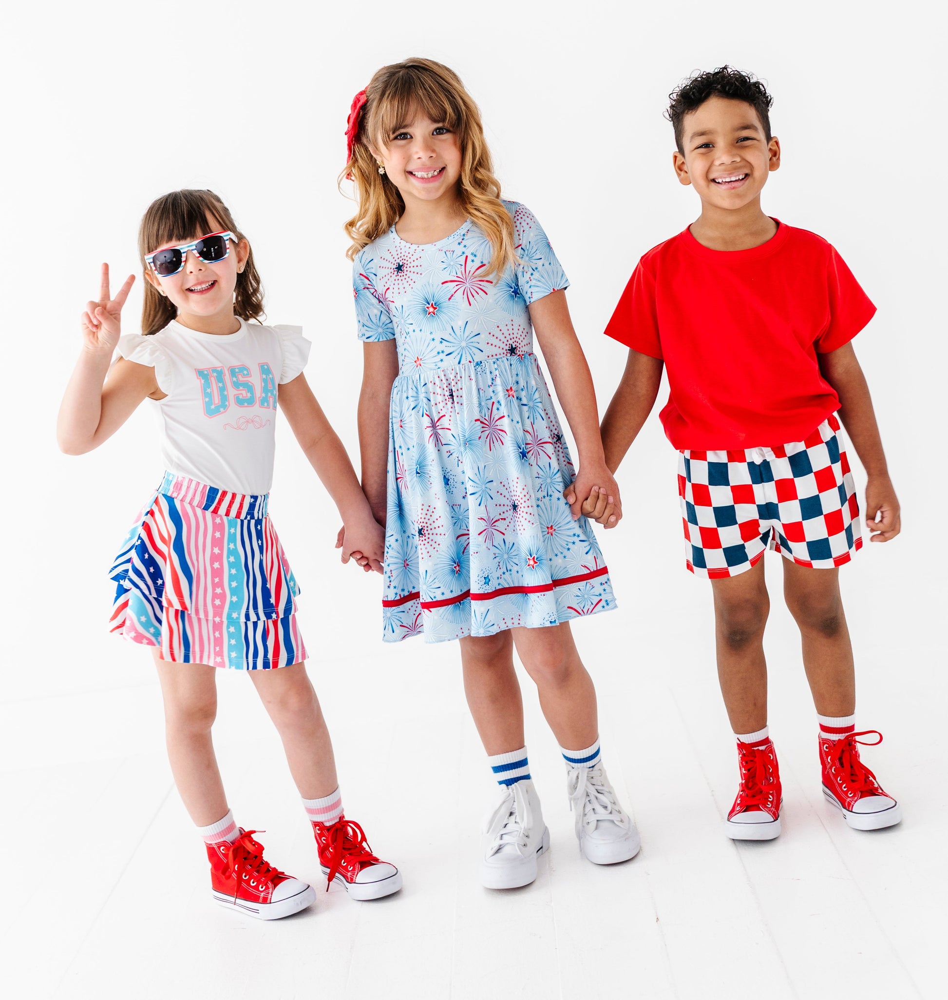 Three children in colorful 4th of July outfits on a white background