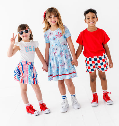 Three children in colorful 4th of July outfits on a white background