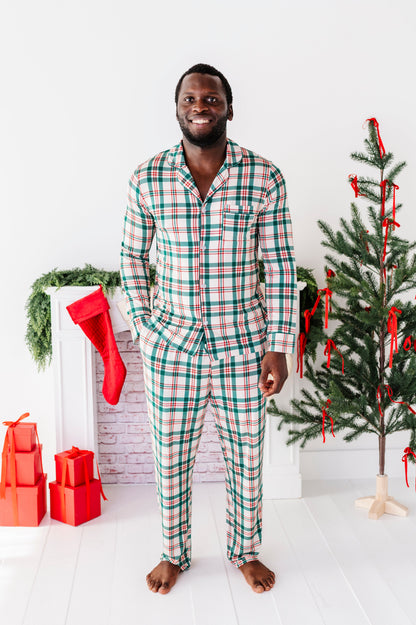A man wearing a classic Christmas plaid lounge set and standing in front of a Christmas tree