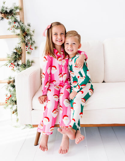 A little boy and his sister wearing coordinating stripe bamboo pajamas featuring various Santa faces all over the pajamas