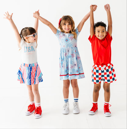 Three children in 4th of July bamboo outfits with raised arms on a white background