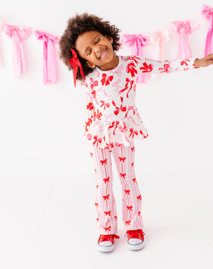 Little girl wearing pink and red ribbon print bamboo cotton pants with red sneakers