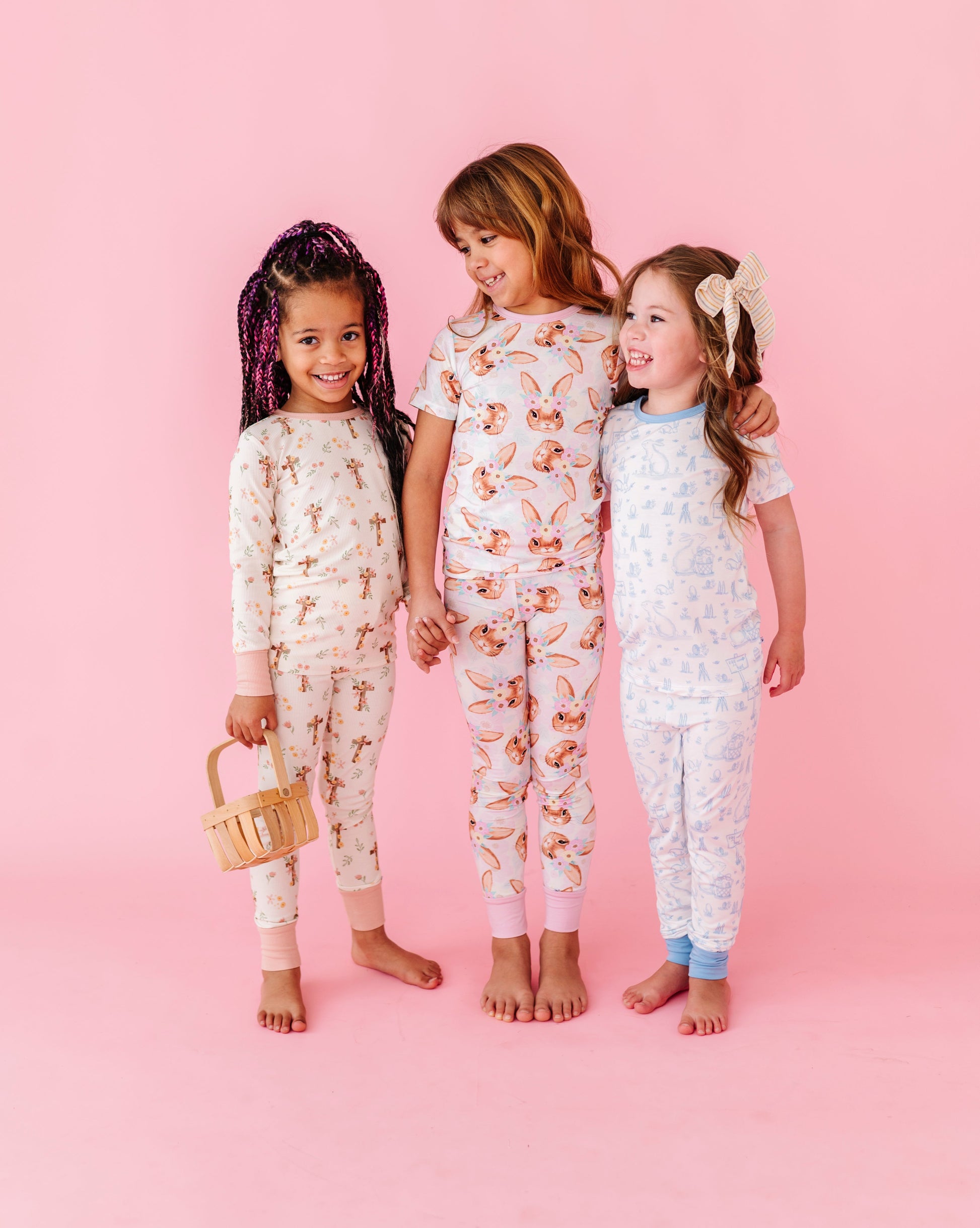 Three children wearing Easter pajamas on a pink background