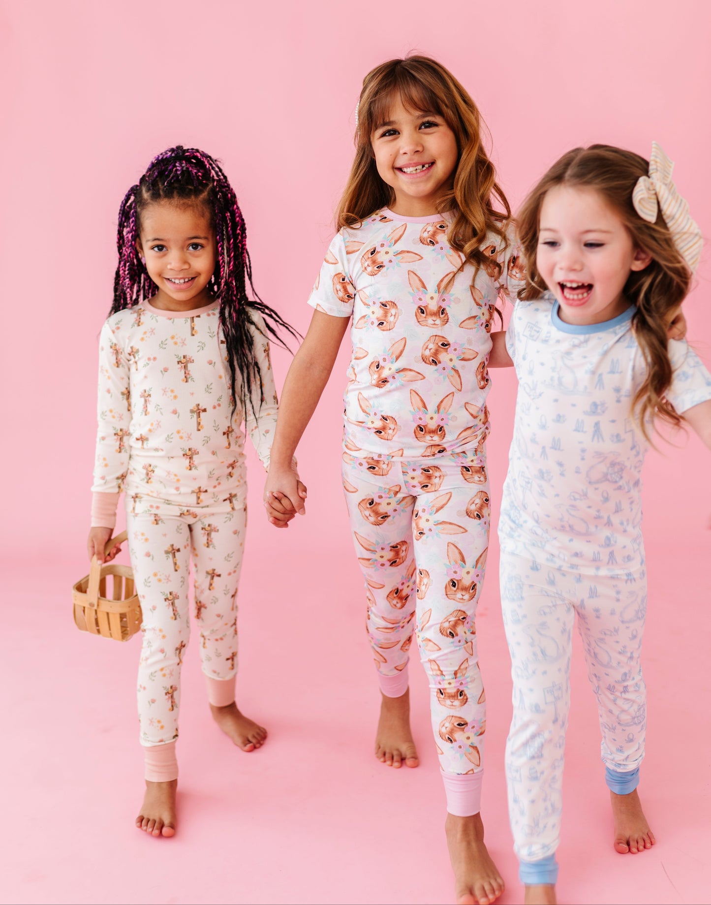 Three children wearing Easter pajamas on a pink background