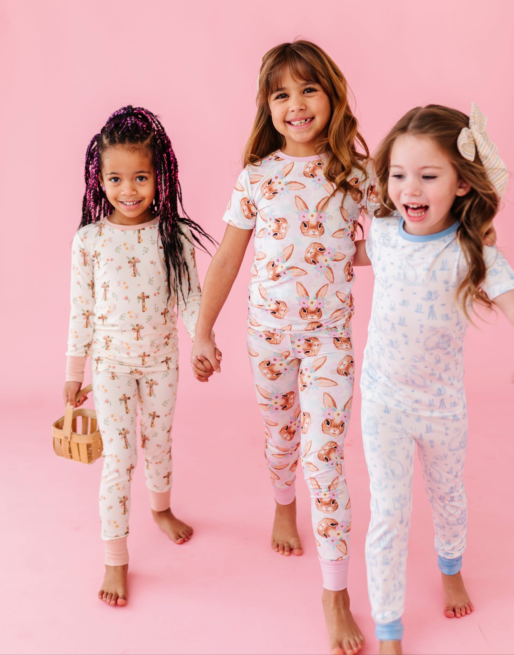Three children wearing Easter pajamas on a pink background