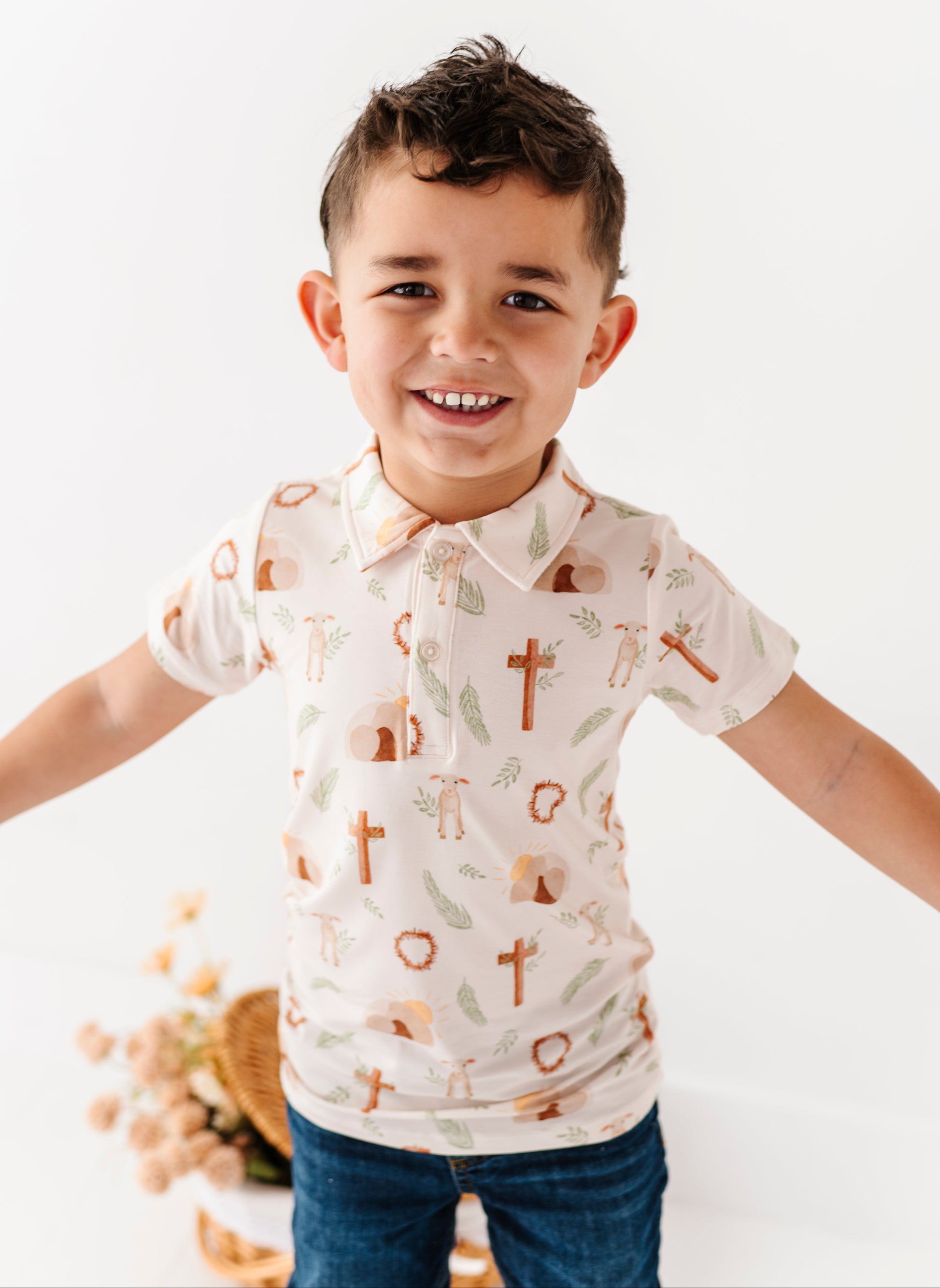 Child wearing an Easter Cross patterned shirt with arms outstretched on a white background
