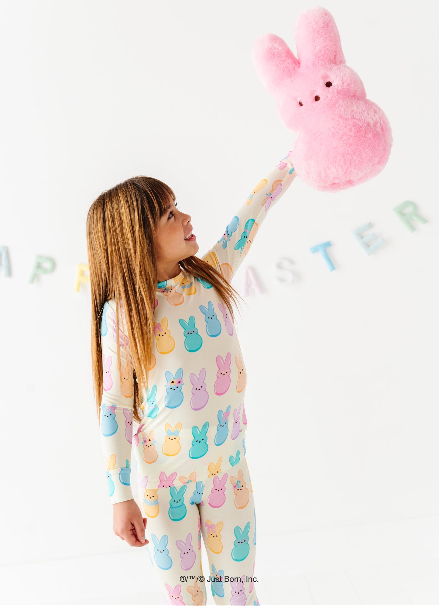 Child wearing PEEPS® pajamas holding a pink PEEPS®  toy against a white background