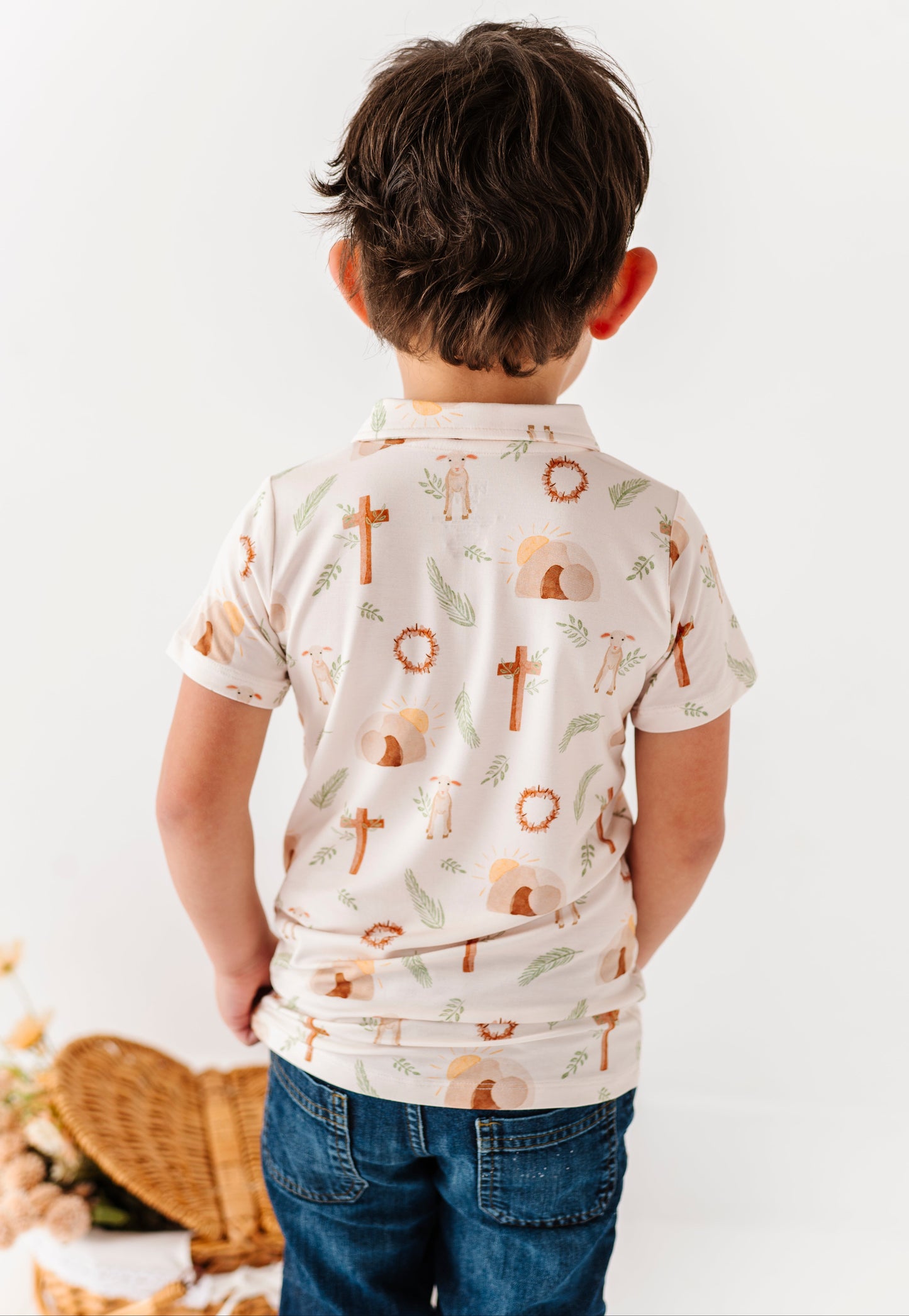 Child wearing a white shirt with Cross pattern for Easter, on a plain background