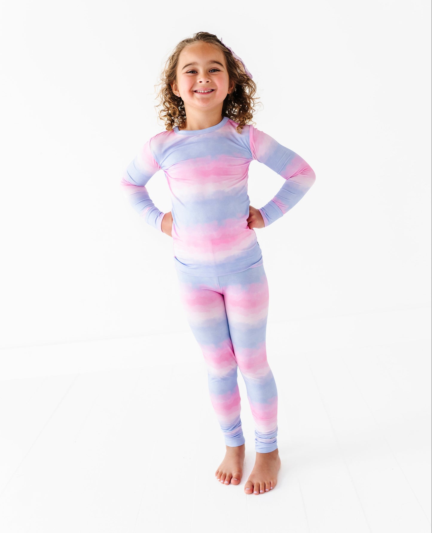 Child wearing a colorful tie-dye bamboo pj set on a white background