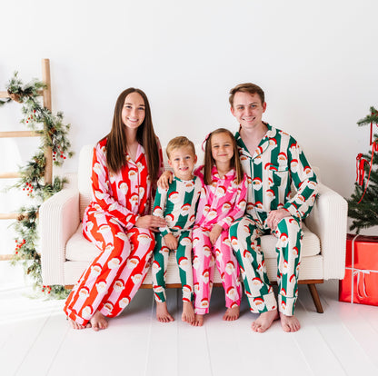 A family gathered beside a Christmas tree wearing coordinating bamboo pajamas. The boys are wearing green stripe pajamas, the mom is wearing red stripes, and the daughter is wearing pink stripes. 