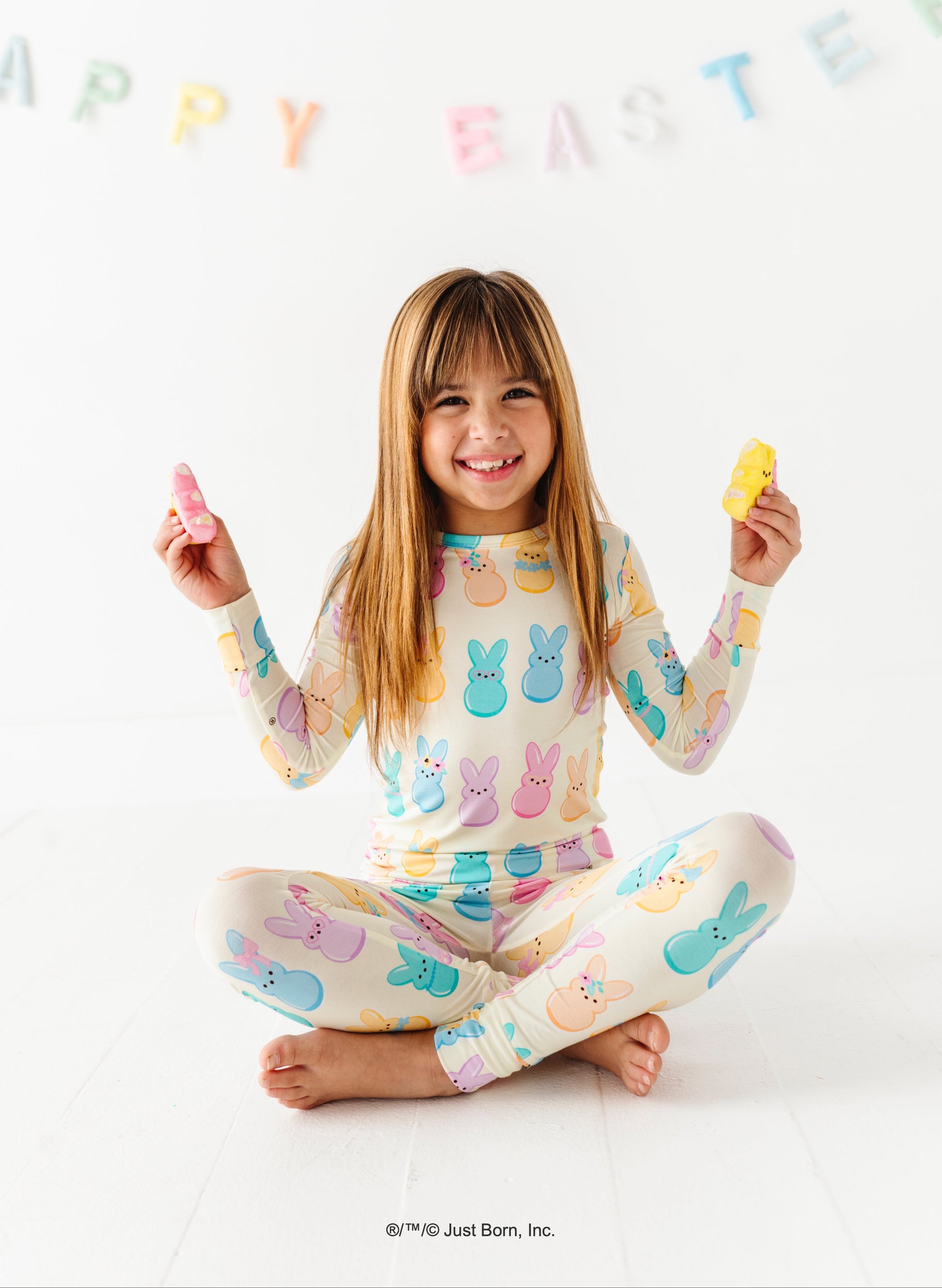 Child wearing a pastel PEEPS® pajama set with 'Happy Easter' banner in the background.