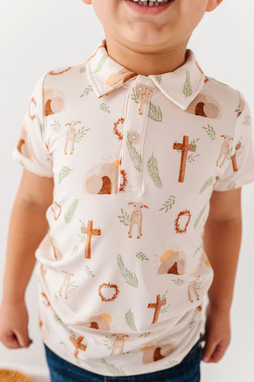 Child wearing a bamboo Easter polo shirt with religious symbols on a plain background