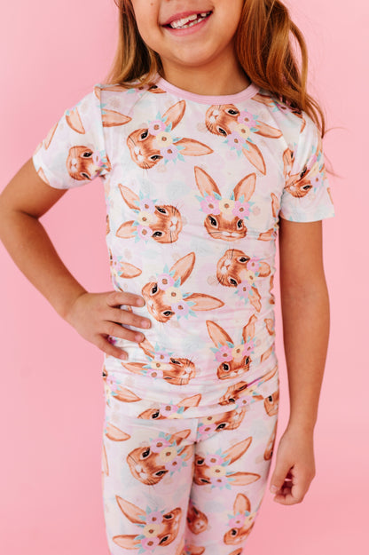 Child wearing an Easter pajama set with bunny print on a pink background