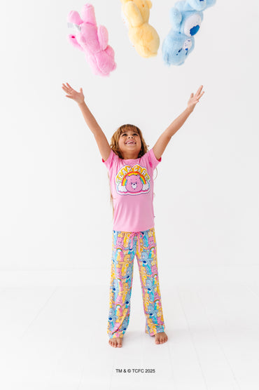 Kid in Care Bears™ Stare bamboo pajama set tossing plush Care Bears toys in the air