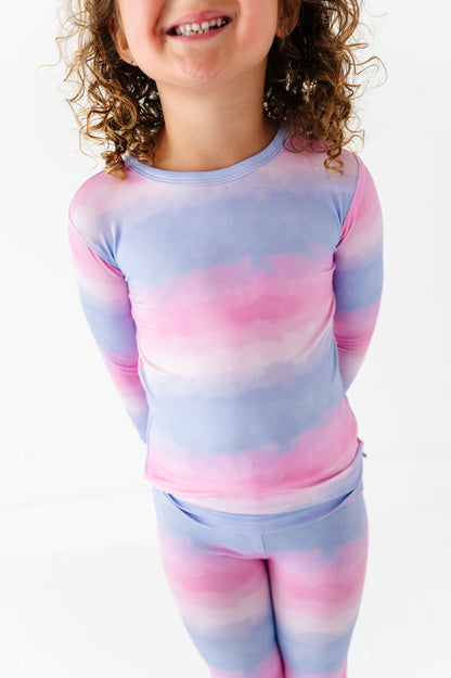 Child wearing a pink and purple tie-dye bamboo pj set on a white background