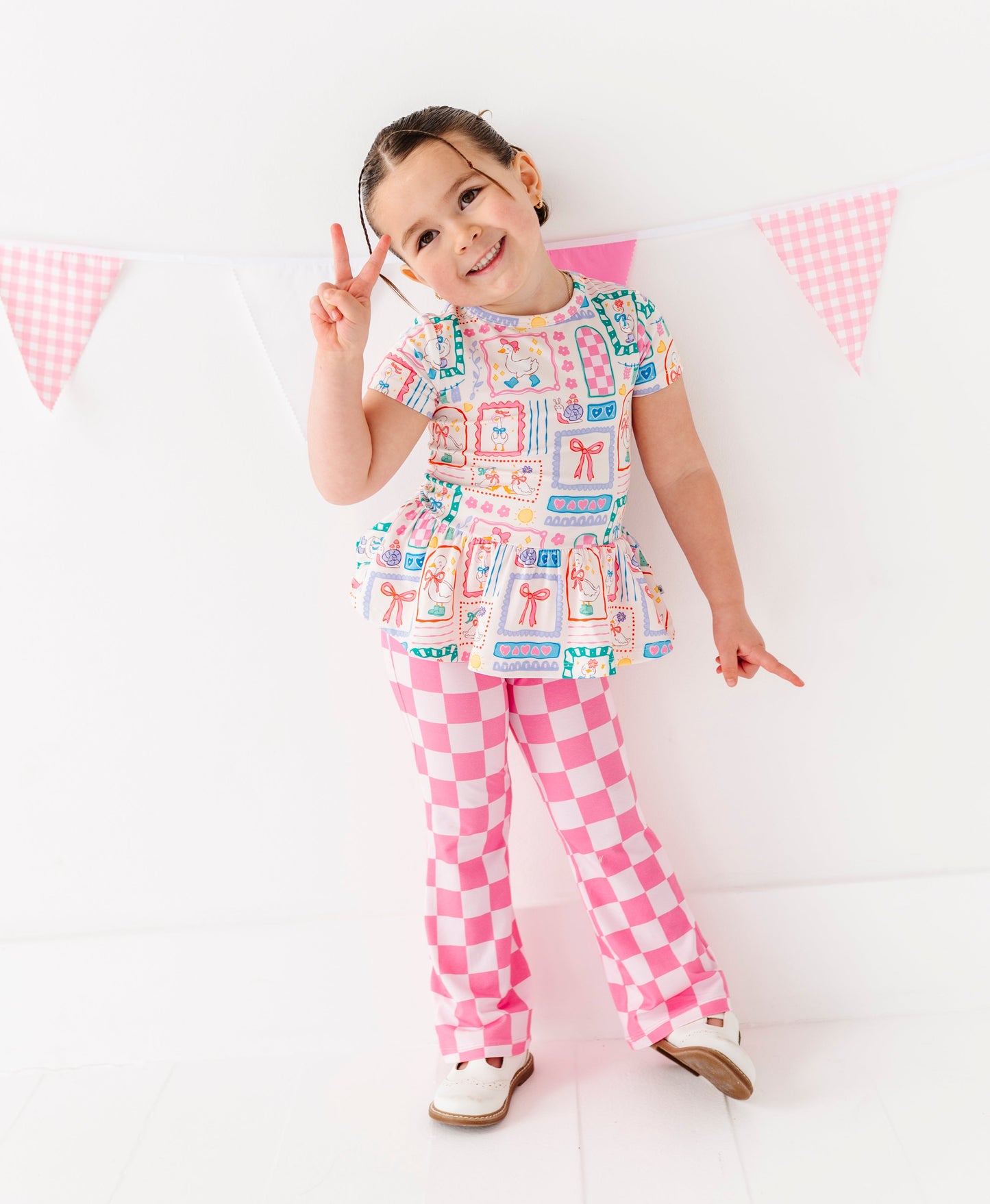Child wearing a colorful outfit with a checkered pattern on a white background
