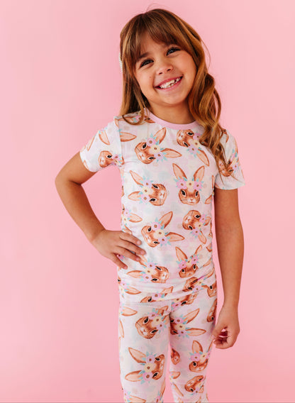 Young girl wearing an Easter bamboo pajama set with animal print on a pink background