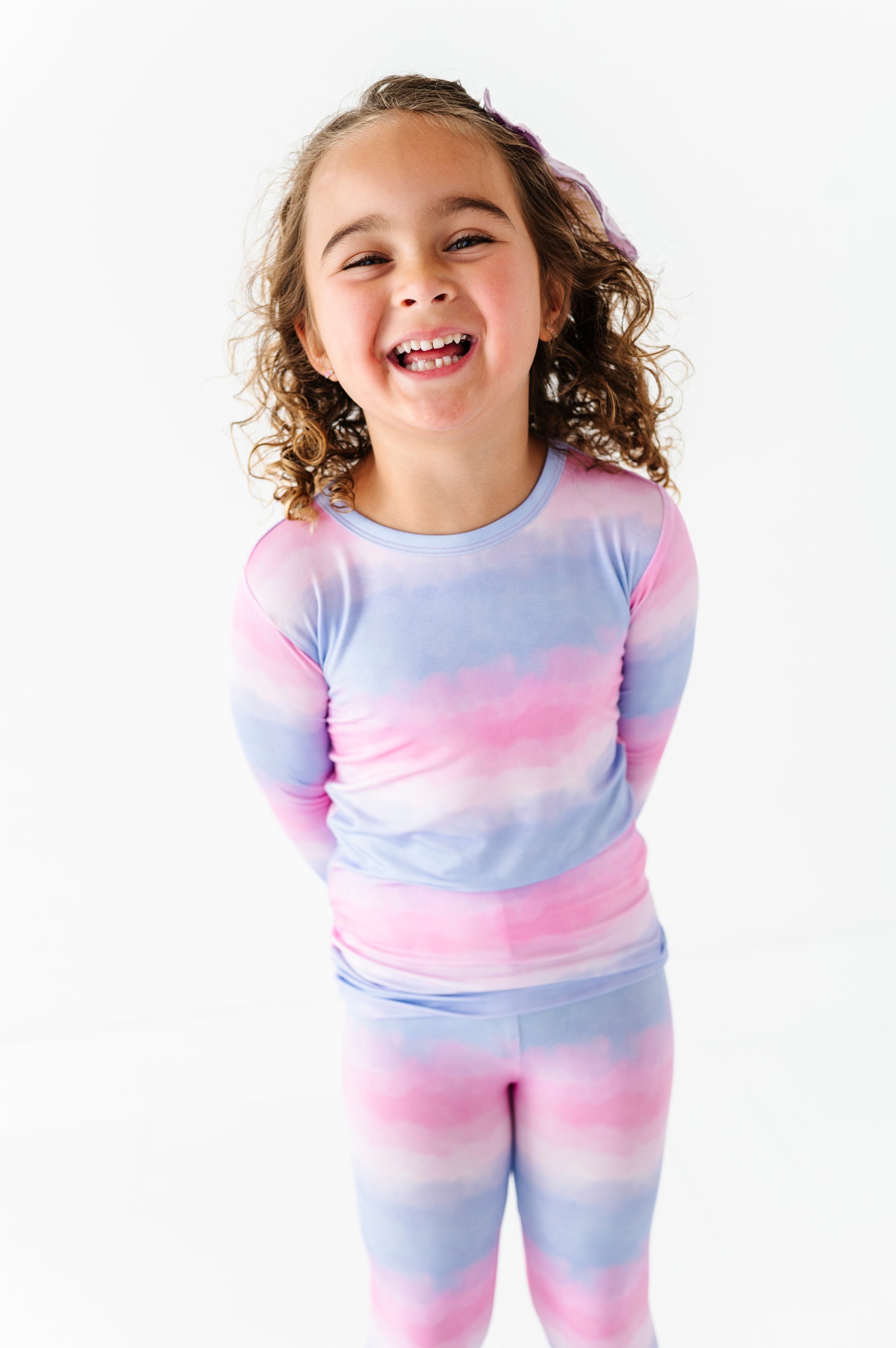 Child wearing a pastel tie-dye bamboo pajama set on a white background