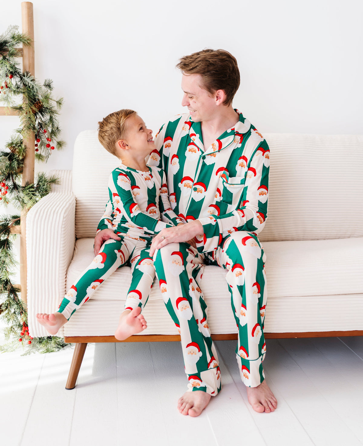 Dad and son wearing matching green stripe bamboo pajamas featuring Santa Claus 