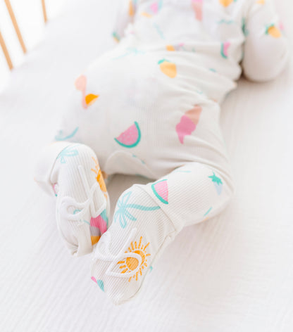 Baby's feet wearing colorful romper with a sun design on a white background