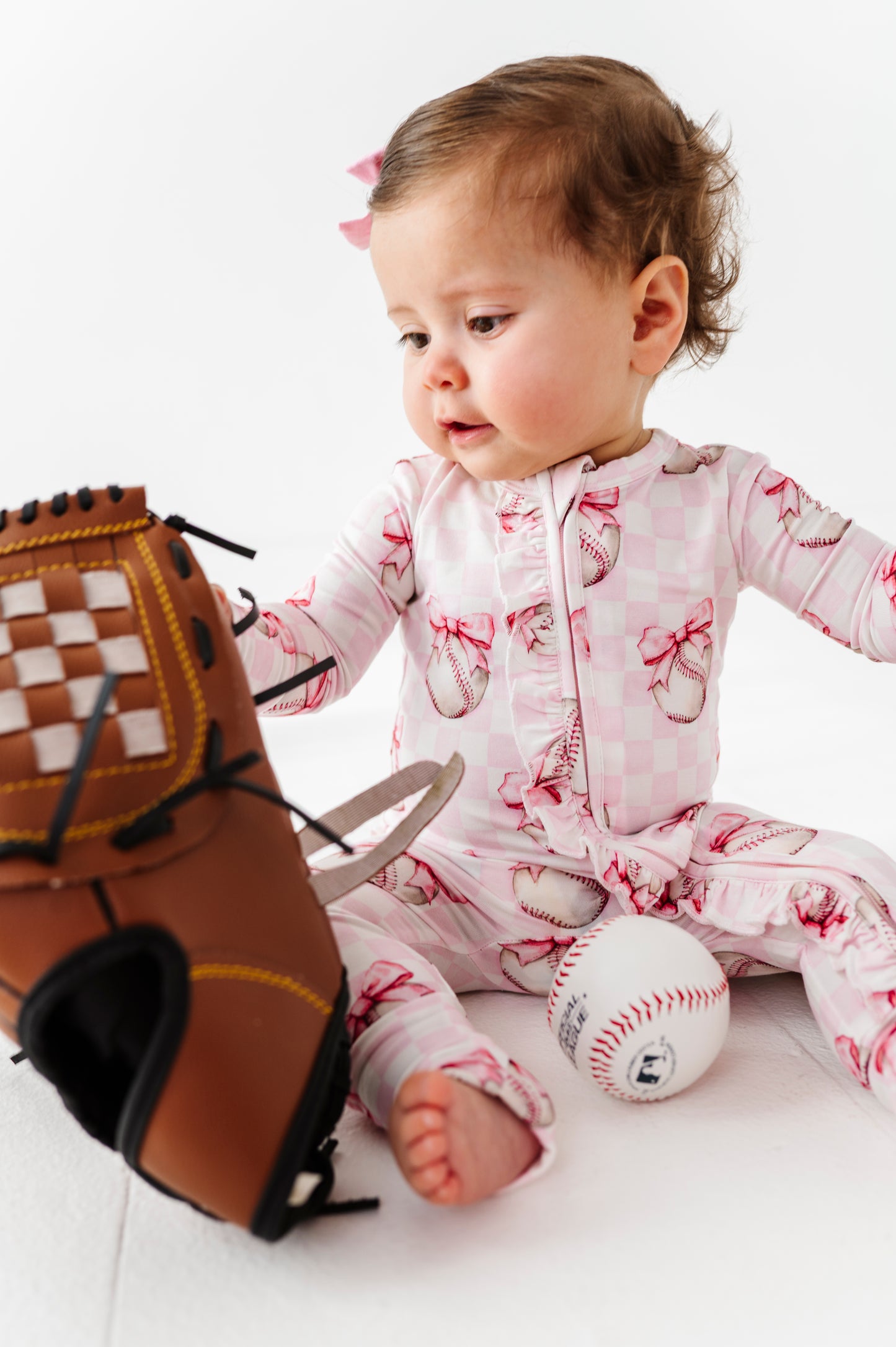Baby in pink check bamboo pajamas with baseball theme