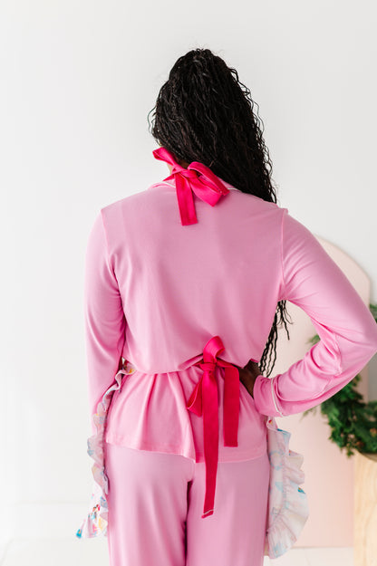 Woman wearing a Sugarplum apron tied around her waist and neck with bright pink bows