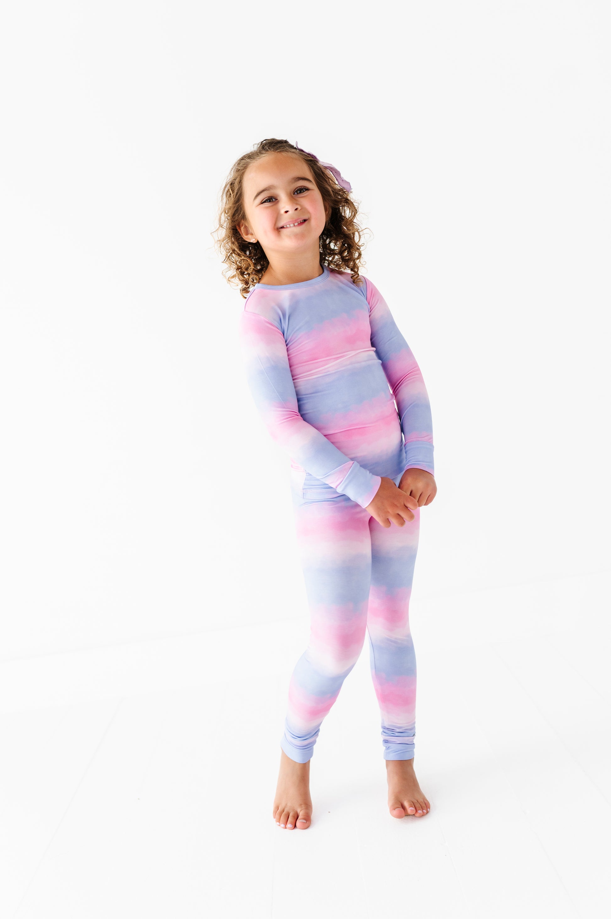 Child wearing a pastel striped bamboo pajama set on a white background
