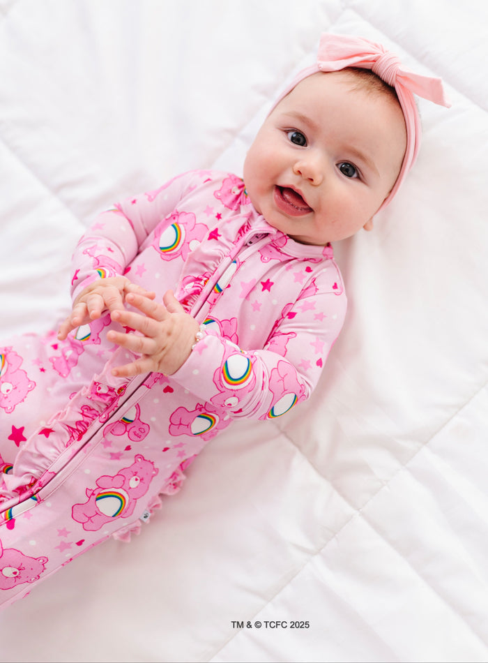 Baby lounging in soft bamboo Care Bears Cheer Bear romper with rainbow accents