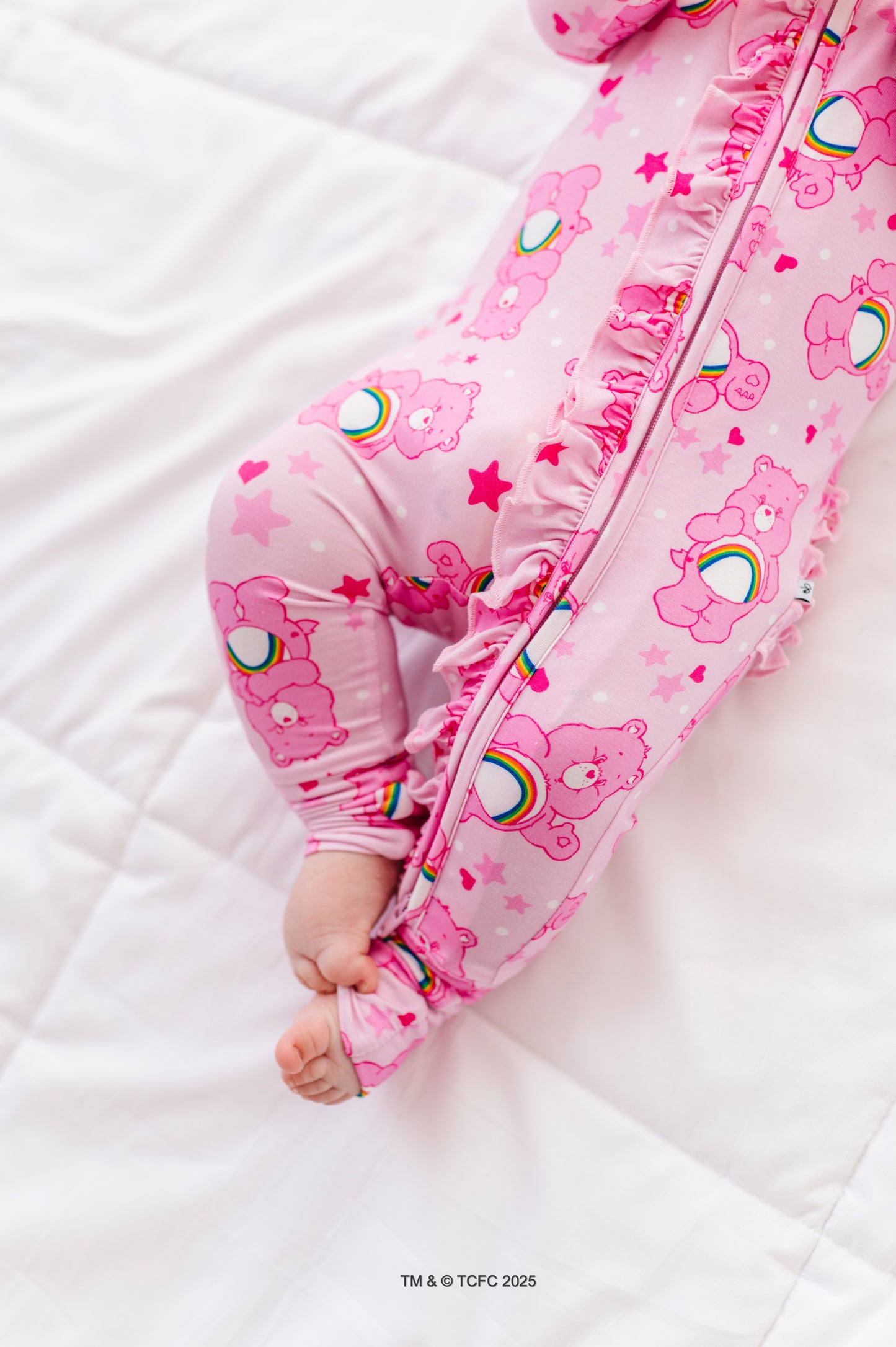 Baby wearing pink Care Bears Cheer Bear convertible romper made from bamboo viscose