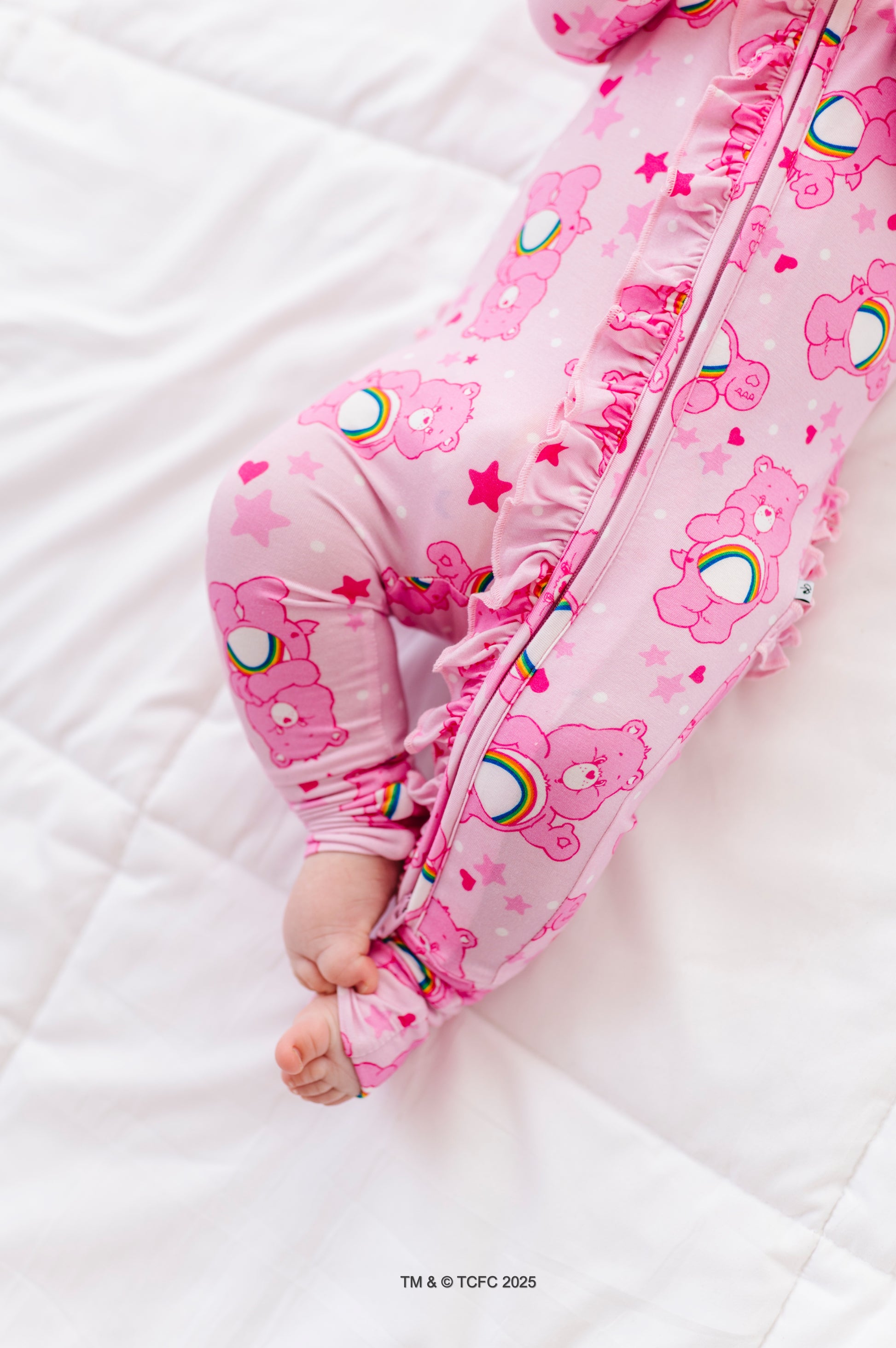Baby wearing pink Care Bears Cheer Bear convertible romper made from bamboo viscose
