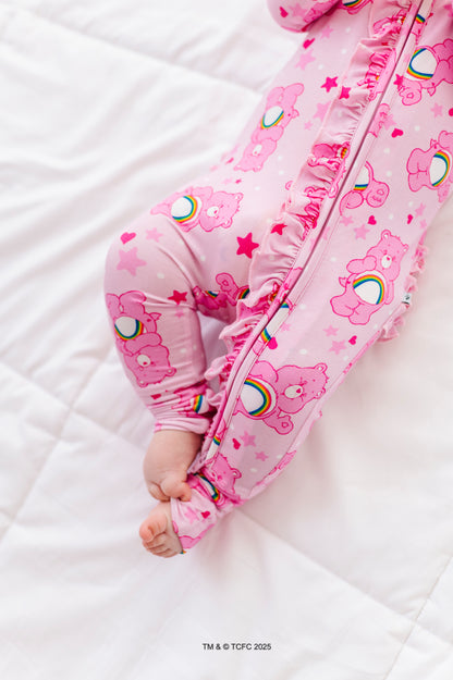 Baby wearing pink Care Bears Cheer Bear convertible romper made from bamboo viscose