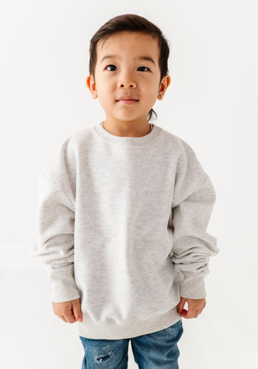 Child wearing a gray sweatshirt on a white background