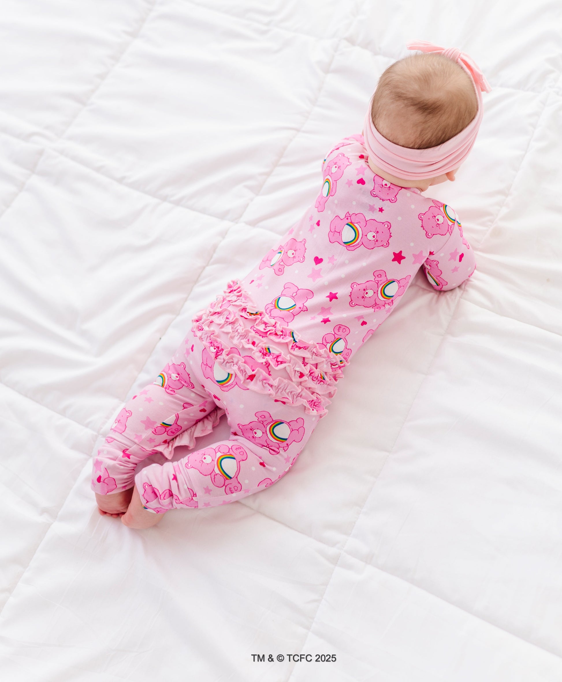 Infant in Care Bears Cheer Bear bamboo romper with ruffles on the back