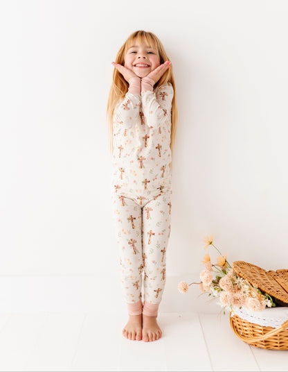 Child wearing a floral bamboo pajama set standing against a white wall with a basket of flowers on the floor.