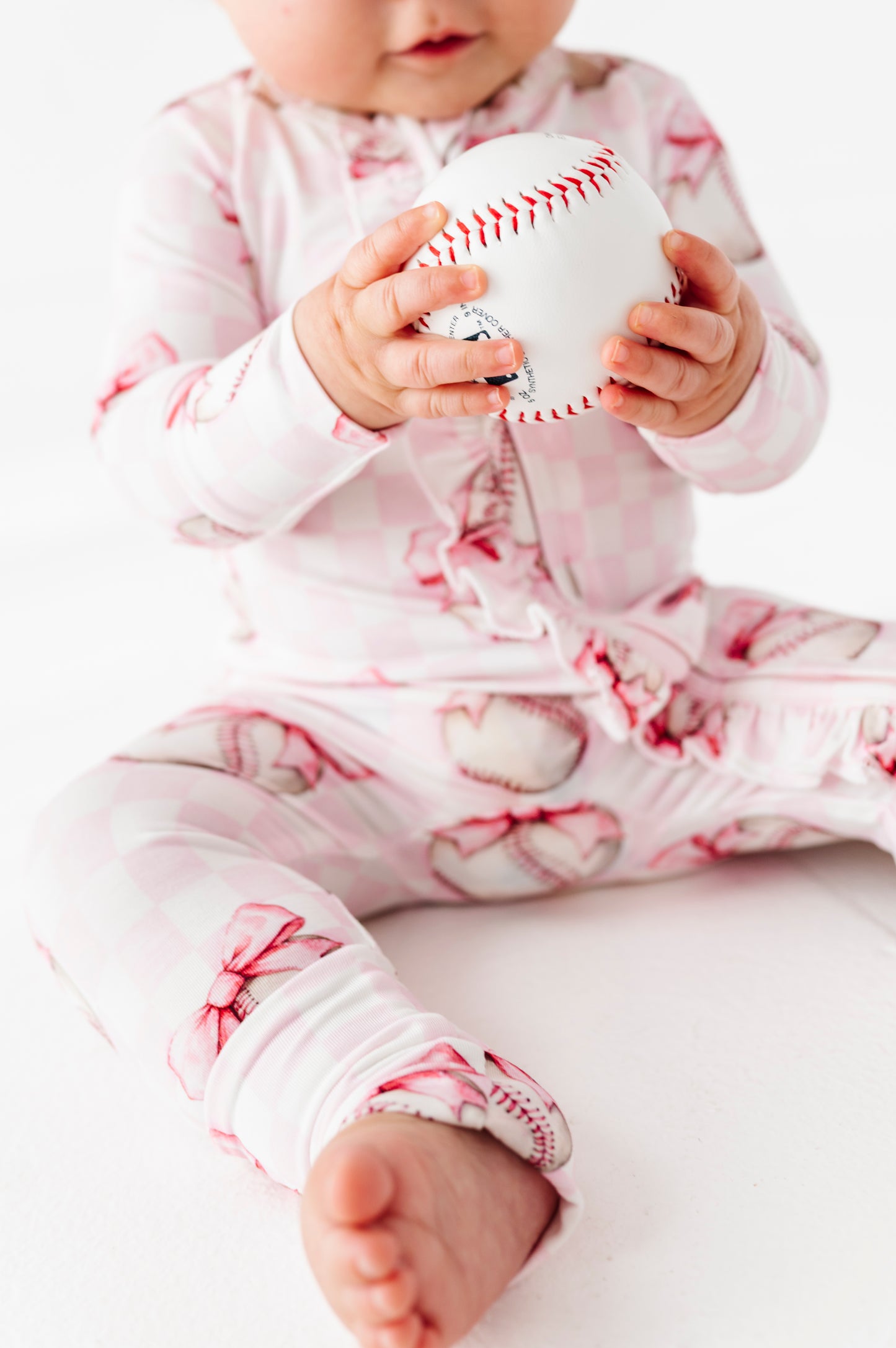 Baby holding a baseball wearing a pink and white bamboo convertible romper  