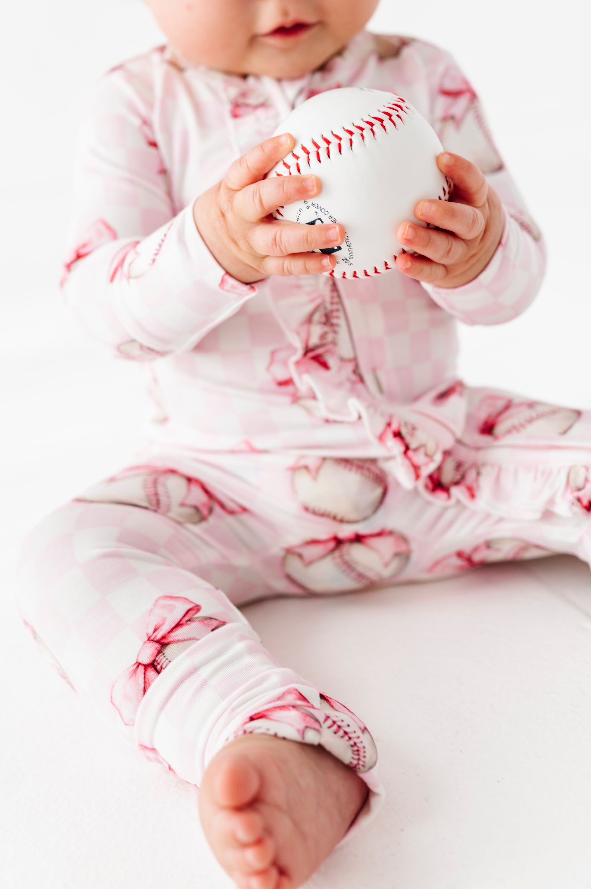 Baby holding a baseball wearing a pink and white bamboo convertible romper  