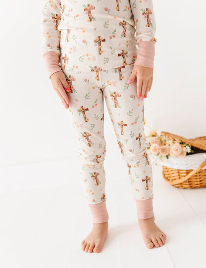 Child wearing Easter pajamas with cross patterns on a white background
