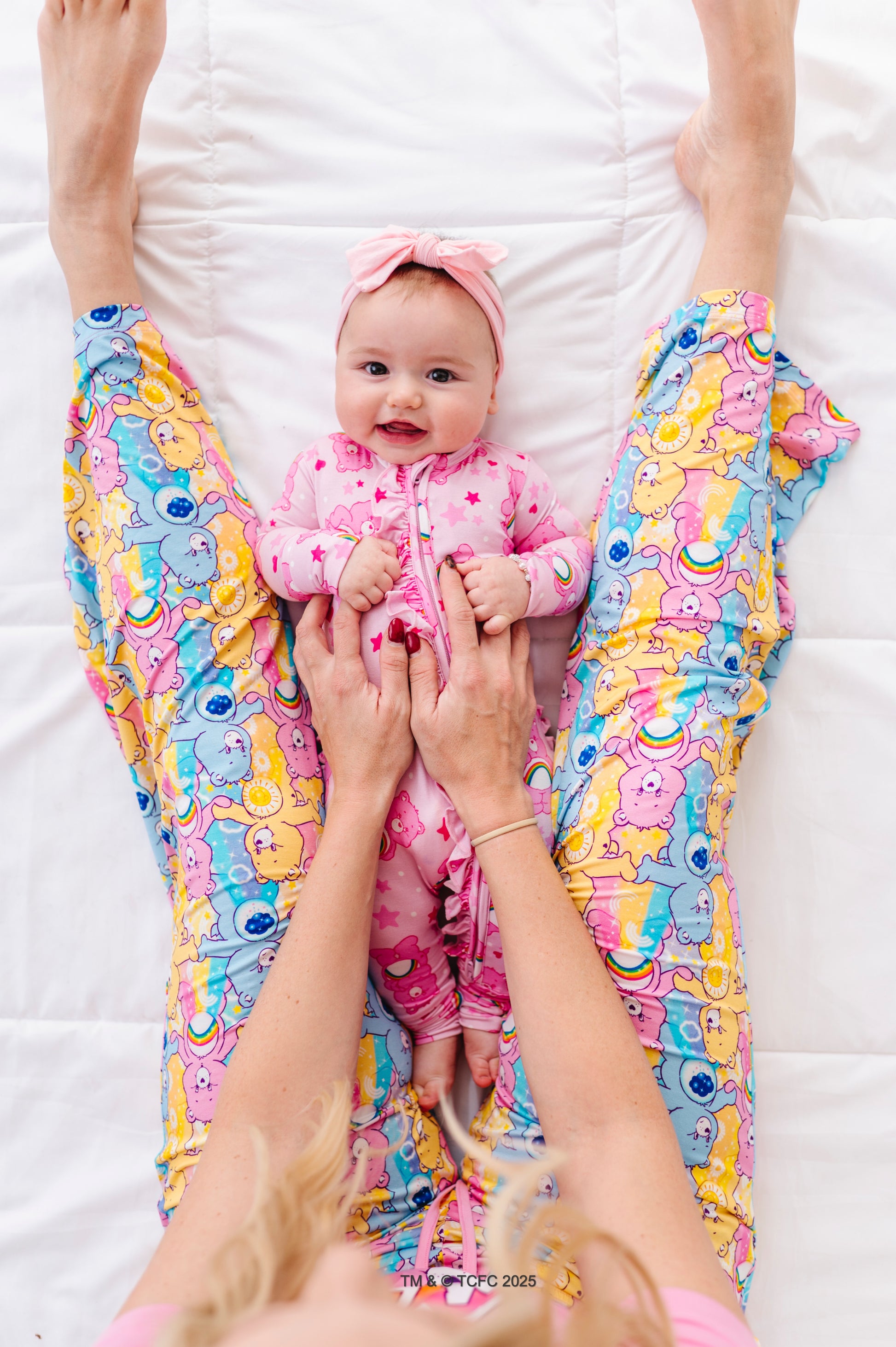 Baby lounging in soft bamboo Care Bears Cheer Bear romper with rainbow accents