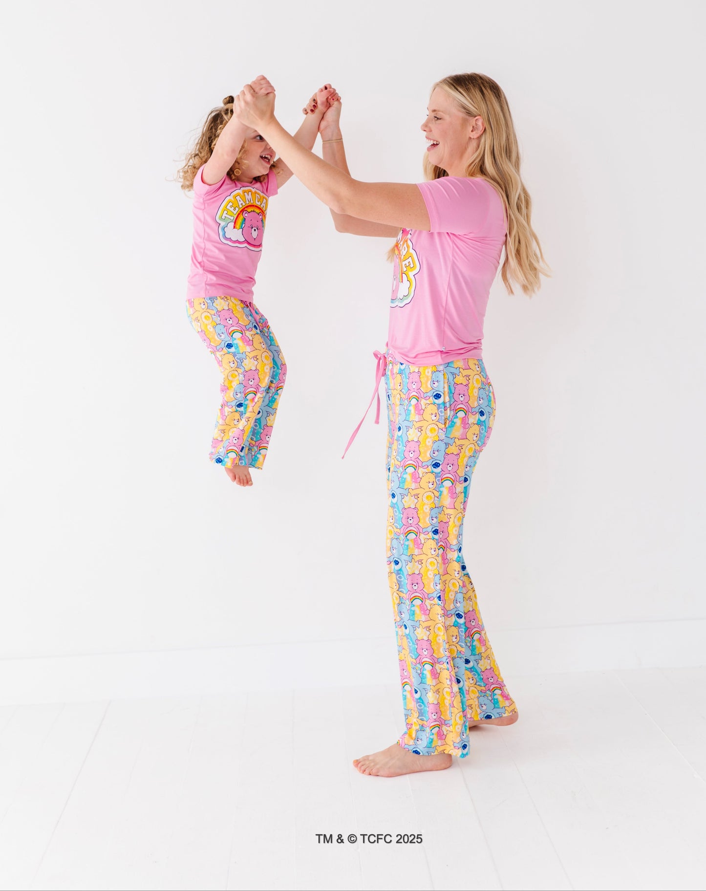 Matching mom and toddler wearing Care Bears bamboo pajama sets on white background