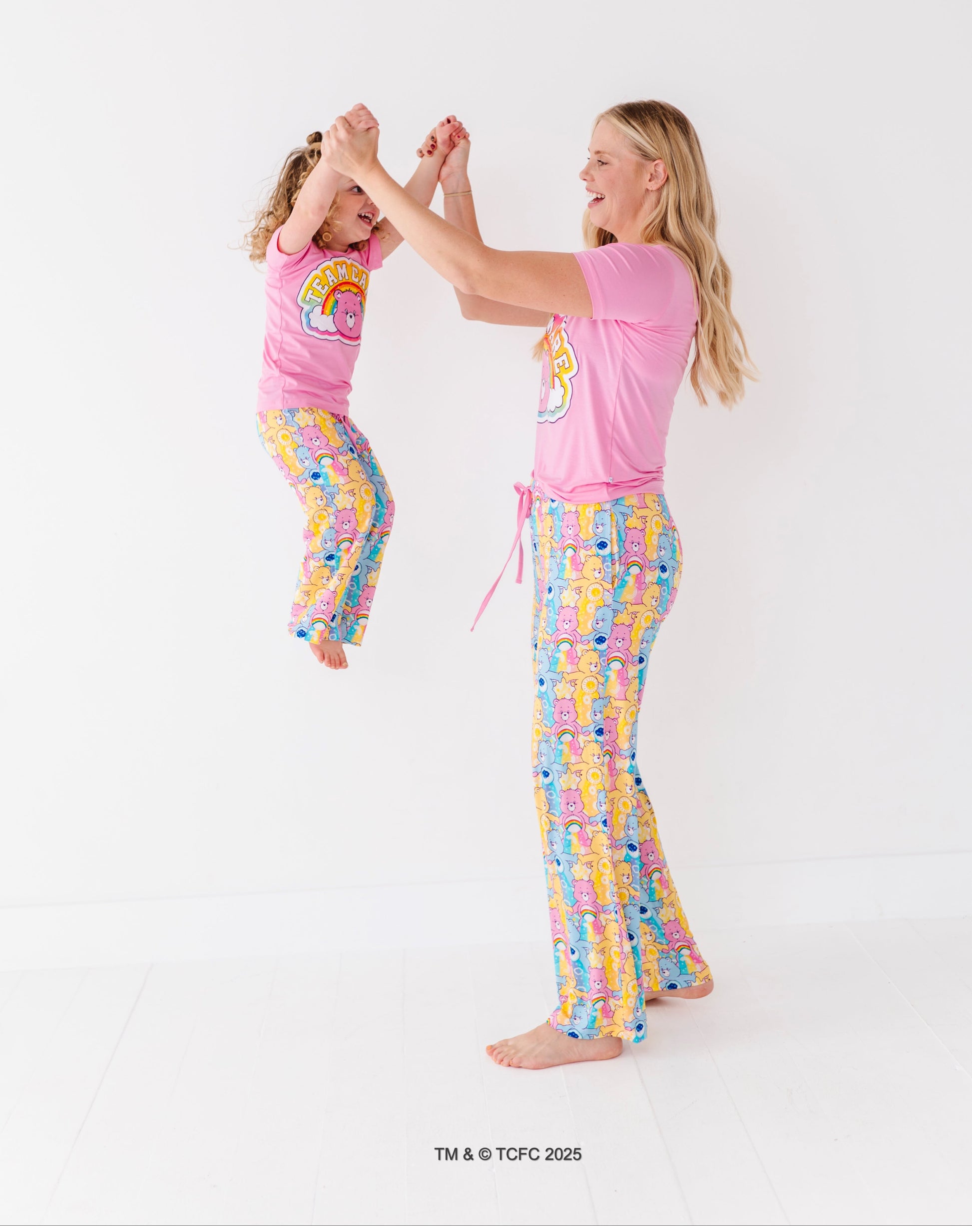 Matching mom and toddler wearing Care Bears bamboo pajama sets on white background