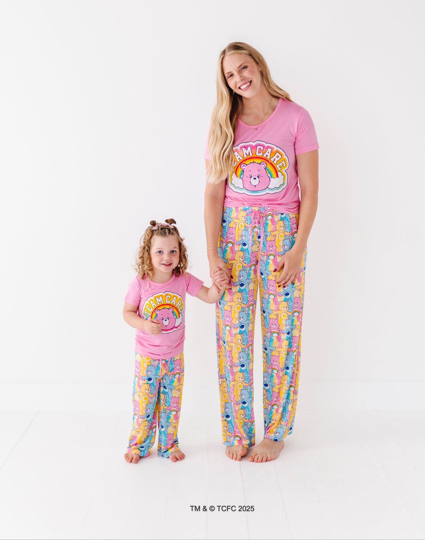Matching mom and toddler wearing Care Bears bamboo pajama sets on white background