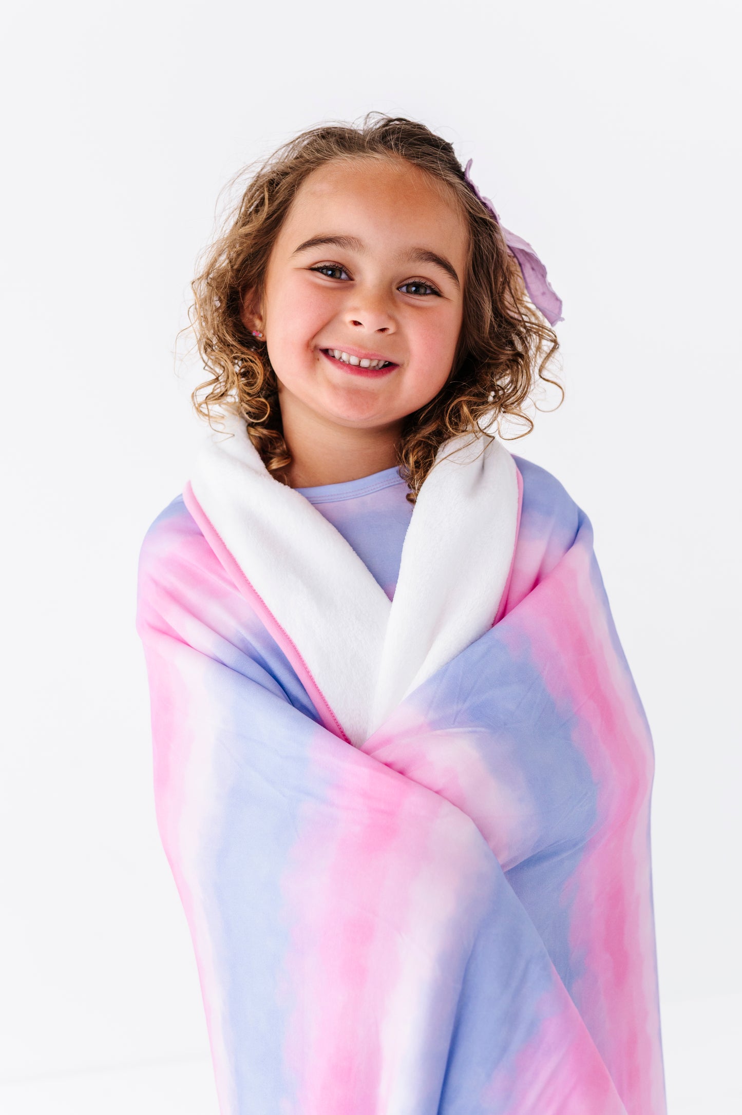Young girl wrapped in a colorful bamboo blanket against a white background