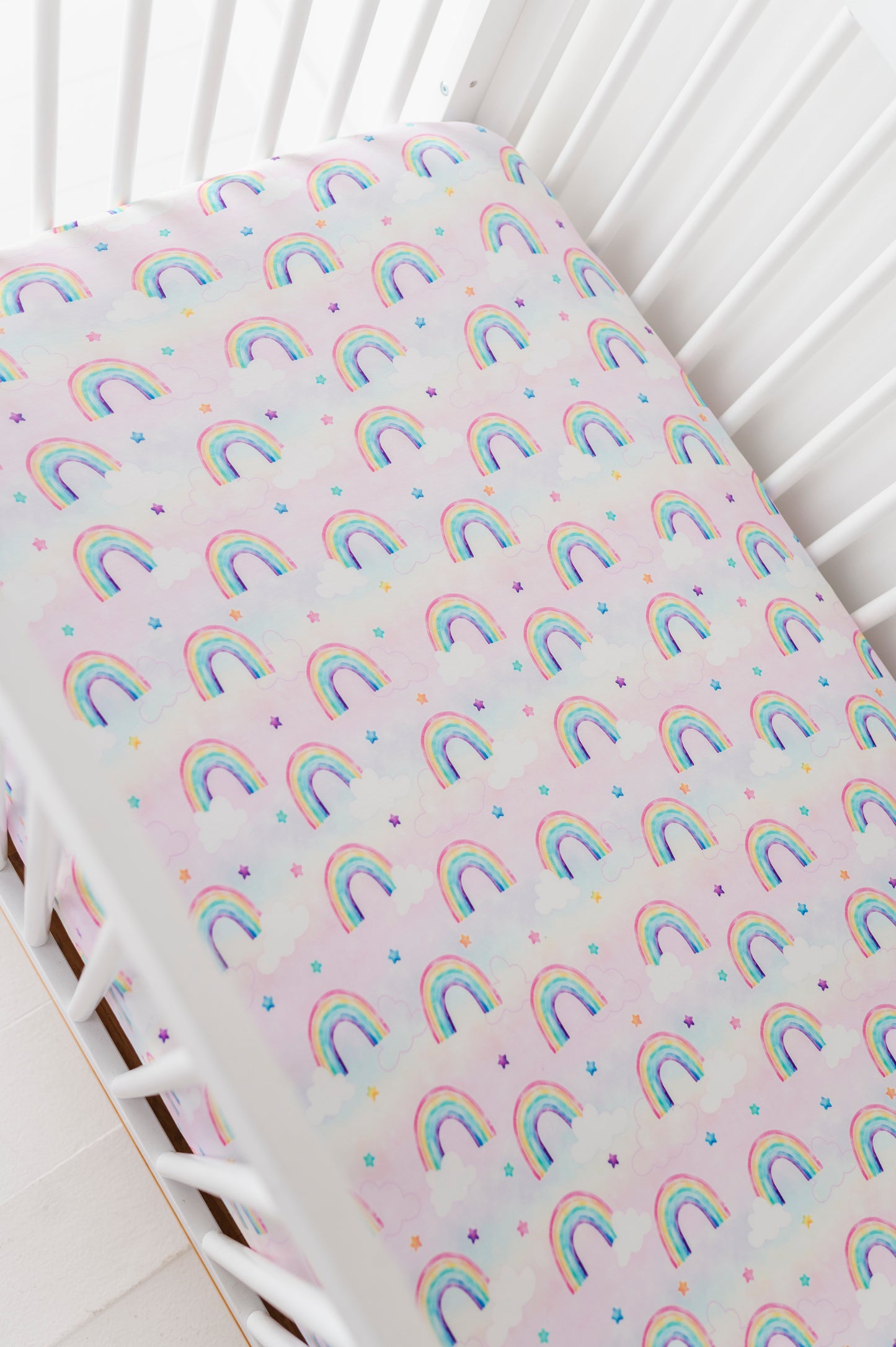 Fitted bamboo crib sheet with rainbow watercolor pattern on a crib