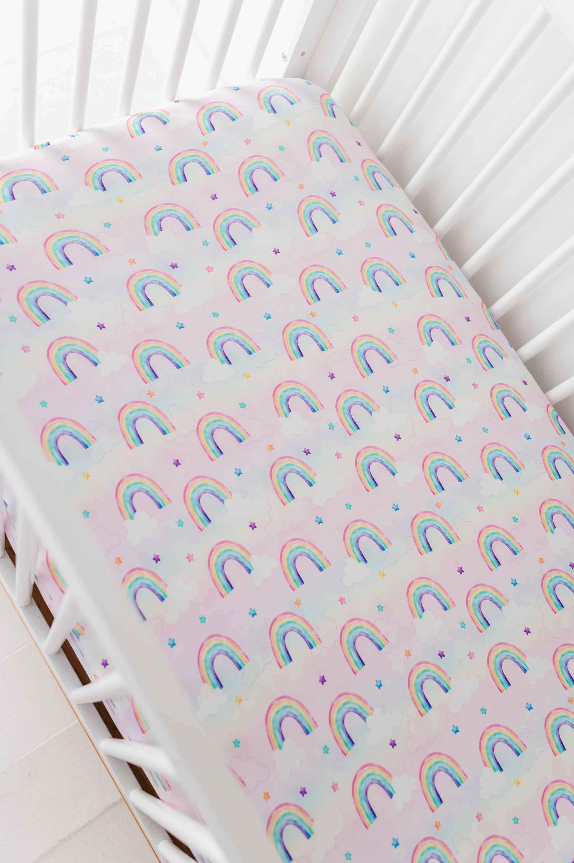 Fitted bamboo crib sheet with rainbow watercolor pattern on a crib