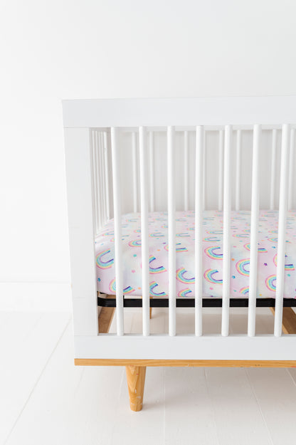 White crib with a colorful bamboo crib mattress on a white floor and wall