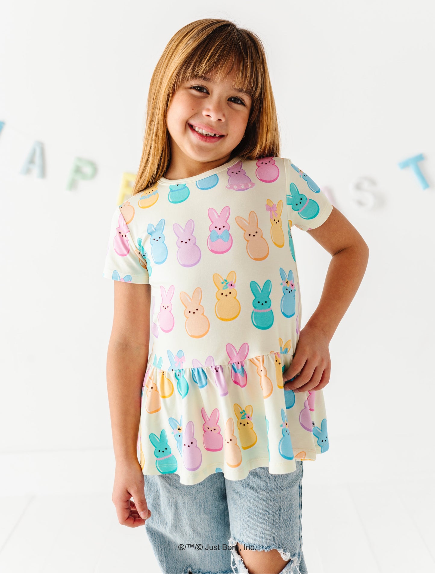 Child wearing a colorful Peeps-themed shirt against a white background