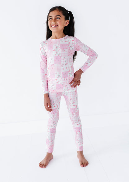 Young girl wearing a pink and white patterned bamboo pajama set on a white background
