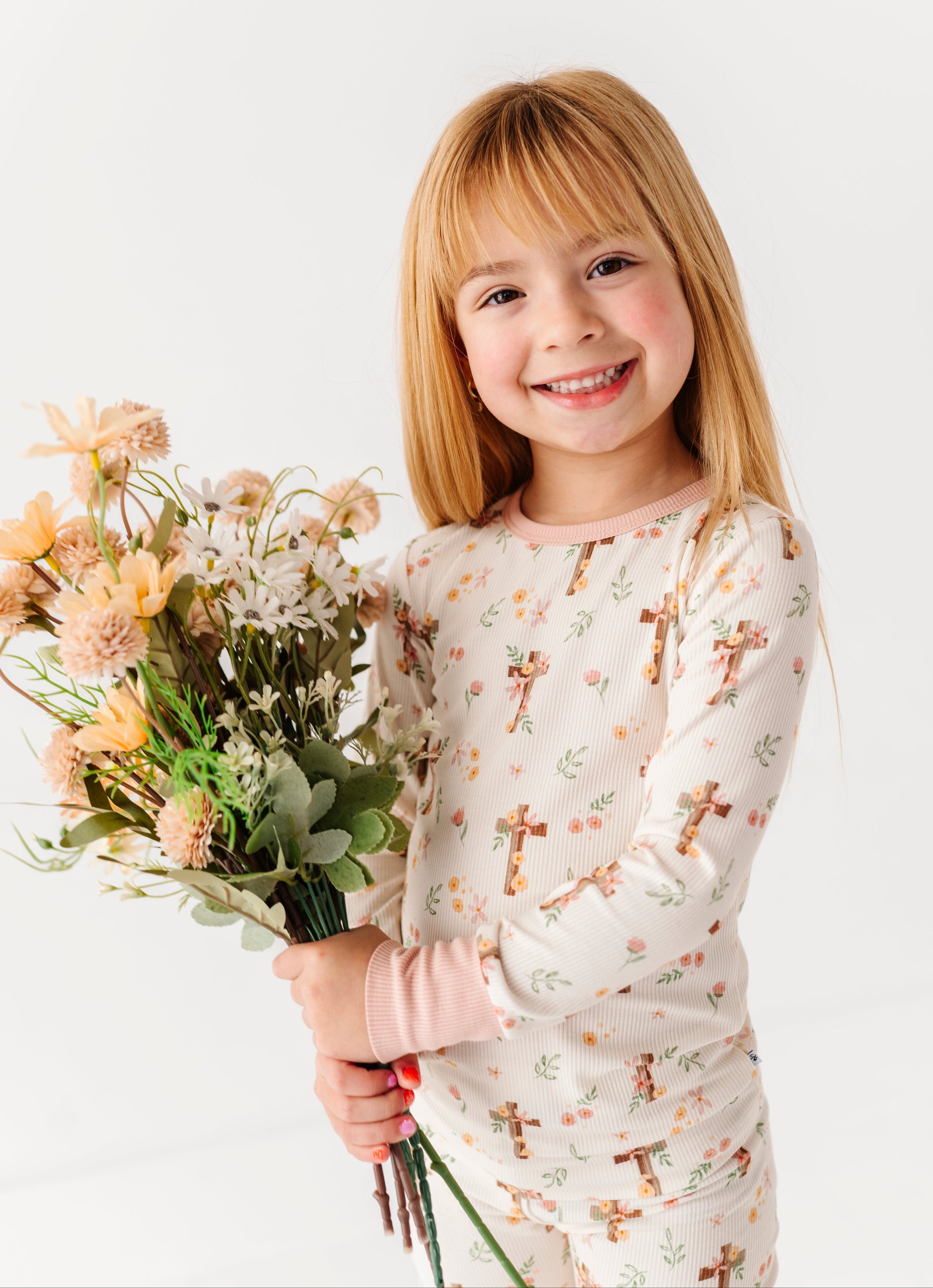 Young girl holding a bouquet of flowers wearing a bamboo pajama set with a floral Easter pattern.